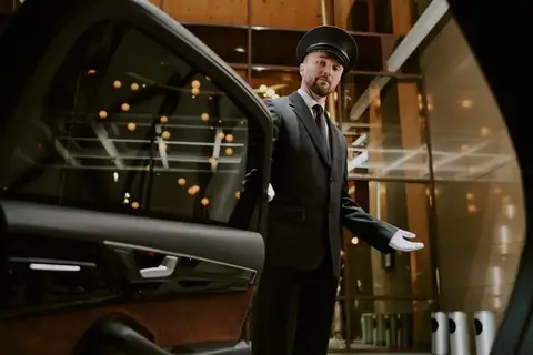 Uniformed chauffeur holding a car door open