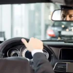 Driver with hands on the steering wheel, seen from the back seat