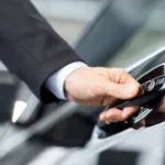 Hand in a suit sleeve opening a black car door